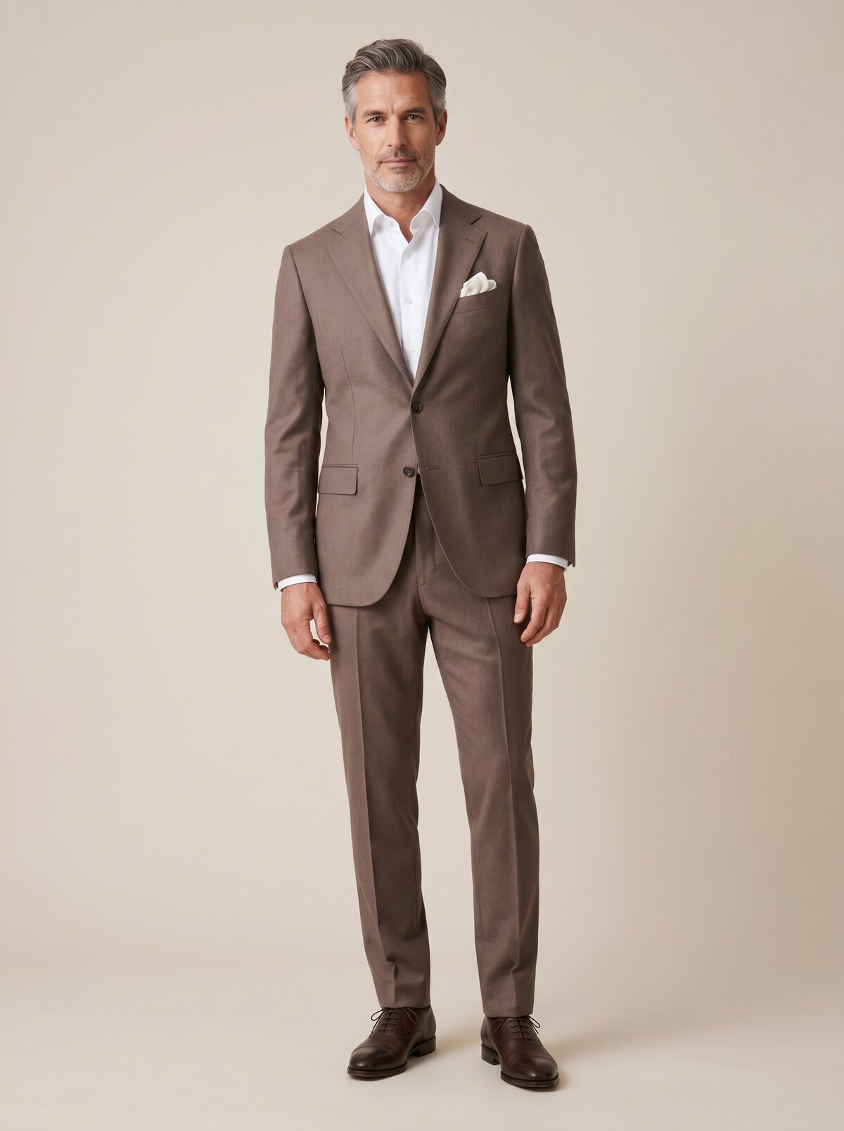 A man in a brown made-to-measure suit with a white shirt and pocket square